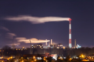 Obraz na płótnie Canvas Industrial district and smoke polluting the air. Lithuania Panevezys Europe. Night sky at winter season.