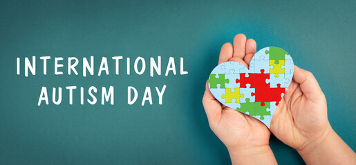 International autism day is standing on the background, hands hold puzzel in the shape of a heart,...