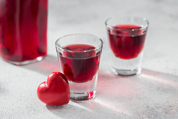 Red cocktail, vodka or liqueur and Heart shape decorations on white background. Happy Valentines day concept.