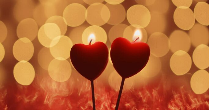 two candles in the shape of a heart burn on a background of beautiful bokeh. valentine's day celebration concept. love two loving hearts