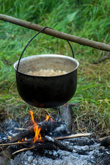cooking porridge in a special bowl on an open fire for a group of tourists