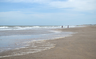 Pareja caminando a lo lejos en la playa un día nublado