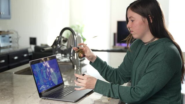 Woman takes remote lesson to learn finger cymbals online on a laptop. Remote learning concept.