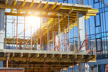 Building construction site work against blue sky.Hydraulic luffing jib tower cranes and workers being poured concrete into foundation. Cement pouring into formwork of building at construction site.