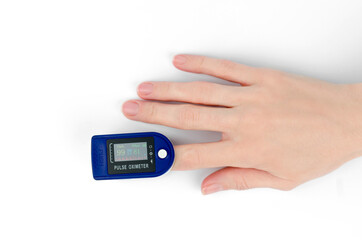 Pulse oximeter on the finger of a female hand, white background. Pulse oximeter shows saturation 99