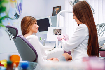 Young woman at the dentist's chair during a dental procedure. Dentist examining patient's teeth in modern clinic. Healthy teeth and medicine concept.