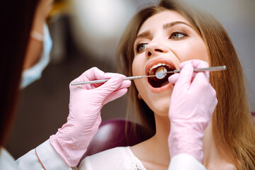 Young woman at the dentist's chair during a dental procedure. Dentist examining patient's teeth in...