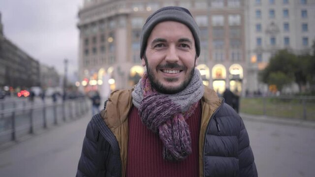 Portrait of a happy man looking at camera with smiling face. Cheerful people in winter clothes standing in a busy city, Crowd in the background