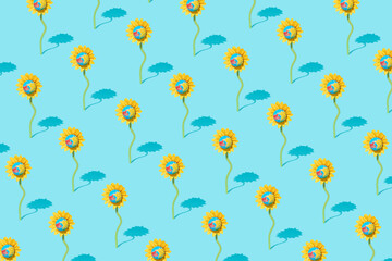 Pattern made of sunflower with planet earth against pastel blue background.  Creative minimal awareness concept.