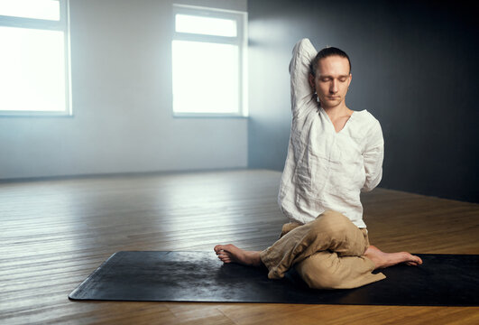 The yogi man do gomukhasana. Yoga practice in the studio.