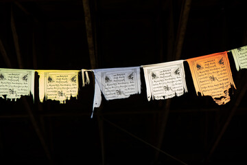 tattered and worn Tibetan prayer flags in closeup against a dark background