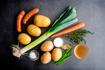 Potato Leek Soup with Andouille Sausage Ingredients: Fresh vegetables, smoked sausage, and spices on a dark background