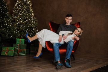 Obraz premium Girl hugging a guy sitting on a red chair