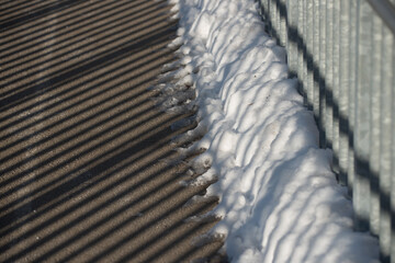 sunlight shadows cast by a metal retaining barrier over a footbridge, winter