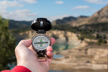 Hand of a hiker holding a compass for orientation in the field.