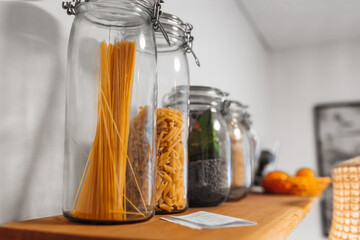 Spaghetti and pasta on a special shelf in glass flasks in the kitchen