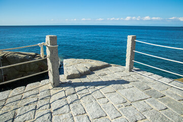Railing with passage to the blue sea on the island of Elba under blue sky in summer