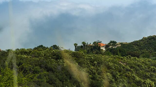 time lapse view of rolling clouds behind a house on the coast stunt road california