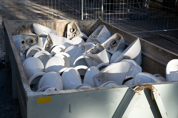 Removed Old used Ceramic toilet bowls lying in the waste Container in Heap for recycling....