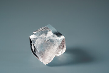 Natural crystal of the mineral raw diamond on a blue background