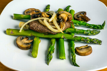 steak resting on asparagus  top with onions and mushrooms