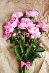 Naklejka na ściany i meble Tender bouquet of pink peonies flowers in sunlight on wrinkled craft paper background