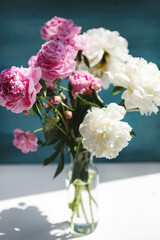 Flower bouquet of pink natural peonies flowers in a vase in sunshine