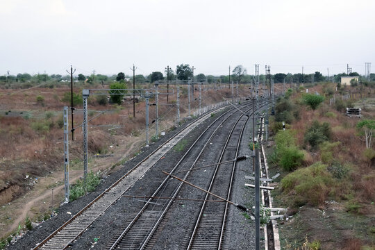 A close-up view of an empty Indian railway track with trees on either side