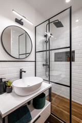 Simple bathroom with black shower, round mirror and classic white tiles - obrazy, fototapety, plakaty