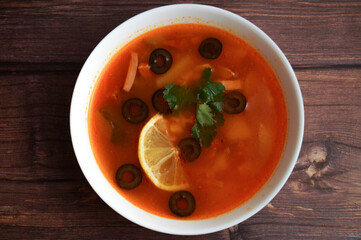 Traditional Russian meat soup Solyanka. Wooden table. Top view.