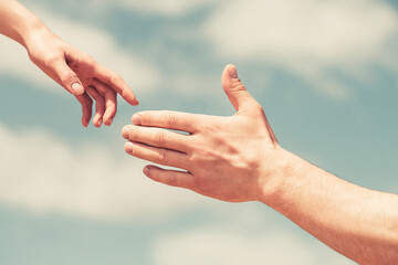 Giving a helping hand. Hands of man and woman on blue sky background. Lending a helping hand. Hands of man and woman reaching to each other, support. Solidarity, compassion, and charity, rescue