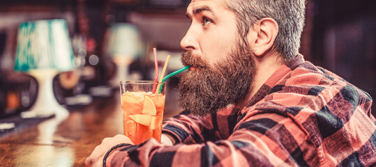 Tropical alcoholic fresh cocktail. Barman in pub or restaurant. Bearded man cocktail. Portrait man, drinking orange juice. Bearded man drink cocktails