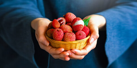 Lychee fruit closeup of woman hands holding vintage wooden bowl of asian exotic fruits litchi. 
