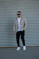 hombre con gafas de sol y chaqueta caminando por la calle