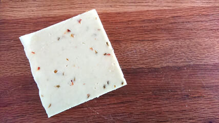 Pepper jack cheese - 1 slice on a wooden cutting board - Powered by Adobe