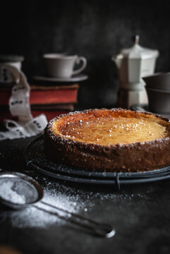 Delicious hot cheesecake on baking pan near glassware on table