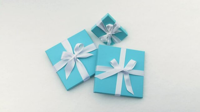 Beautiful teal blue boxes with white satin ribbon and simple bows isolated on white snow background. Background footage symbolizing love, Valentine Day, Womens Day, Birthday, Wedding Anniversary 6K