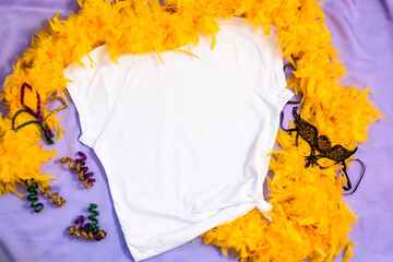 Mockup white t-shirt decorated yellow feather boa and carnival mask. Mardy Gras apparel flatlay on...