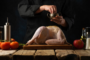 The chef prepares a festive dish of poultry. Chicken and turkey on cutting board. The chef sprinkles the carcass with spices. Ingredients. Restaurant, hotel, cafe, home cooking.