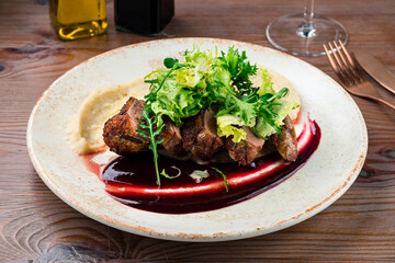 Grilled duck meat with salad on plate. Closeup.