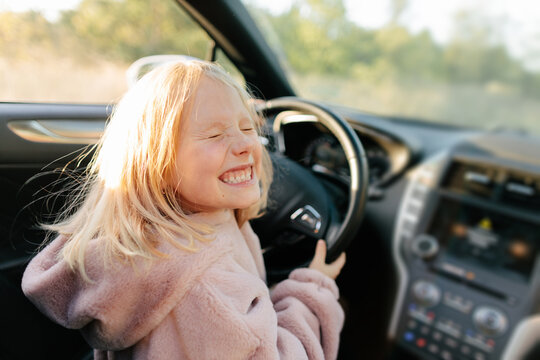 Happy girl sitting on driver seat