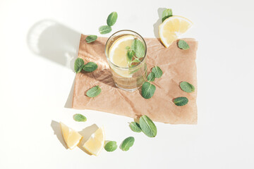 Composition made of mint leaves, lemon slices, and glass. Refreshment summer concept with shadow. Bright drink arrangement.