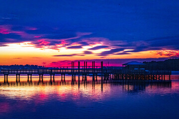 A colorful blue hour sunset of a pier with a bridge in the background off of Hilton Head Island with a nice reflection in the water.