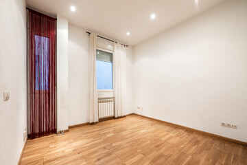 Empty room with light oak wooden floor, aluminum radiators and red and white curtains