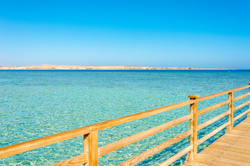 wooden pier against blue sky and turquoise sea on a sunny day in egypt, sahl hasheesh
