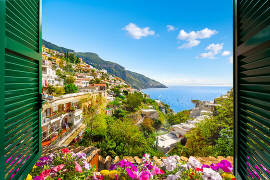 Fototapeta Mountain, city and sea view through an open window with shutters of the city of Positano on the Amalfi Coast of Southern Italy during summer.