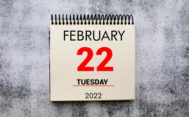 february 22. 22th day of month, calendar date. Stand for desktop calendar on beige wooden background.