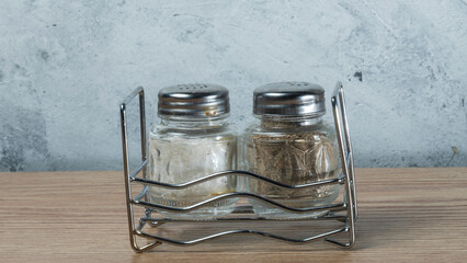 Modern Salt and Classic pepper grinders standing on wood texture table. Salt and pepper shaker on...