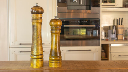 Modern Salt and Classic pepper grinders standing on wood texture table. Salt and pepper shaker on...