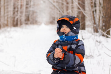 boy thinking in winter park. the boy folded his hands in the lock and seemed to be praying. he looks at the sky. concept of children's new year wishes